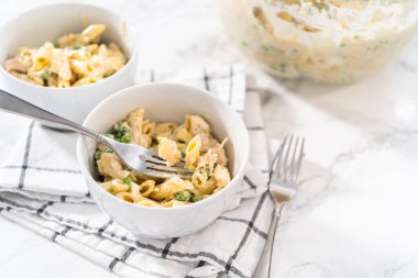 Beyaz seramik kaselerde tavuklu makarna salatası..