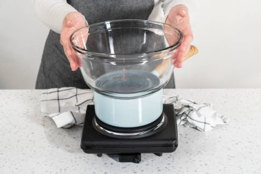 Melting white chocolate chips and other ingredients in the double boiler to prepare chocolate pistachio fudge.