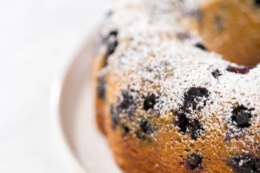 Taze pişmiş limonlu yaban mersinli kek dilimliyorum. Pudra şekerli..