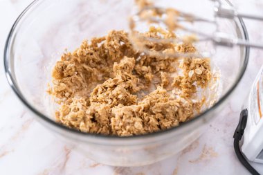 Elmalı yulaflı kurabiye pişirmek için büyük bir bardakta karıştırma malzemesi..