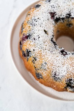 Taze fırınlanmış limonlu yaban mersinli kekin tozunu alıyorum..