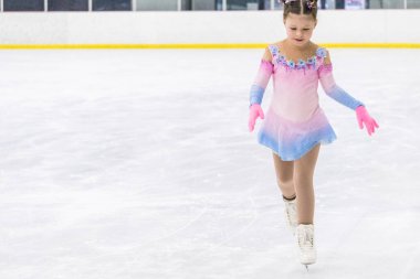 Küçük kız buz pateni pistinde artistik patinaj yapıyor..