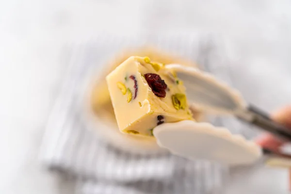 stock image Holding homemade cranberry pistachio fudge square piece with kitchen tongs.