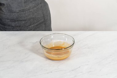 Mixing ingredients with a hand mixer in a small mixing bowl to make the caramel filling for bundt cake.
