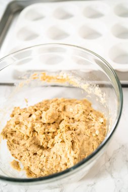 Muzlu yulaf ezmeli kek pişirmek için Lale kağıtlı kek dilimleriyle kaplanmış kek tepsisine hamur kepçesiyle hamur toplamak..