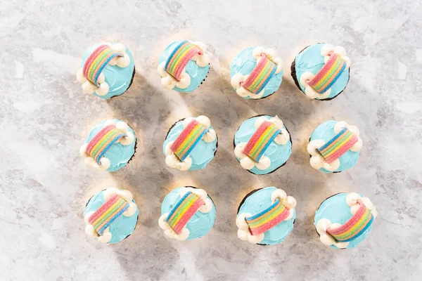平置きだ ブルーバタークリームのフリスティングとユニコーンのテーマの誕生日パーティーのための虹で飾られたチョコレートカップケーキ — ストック写真