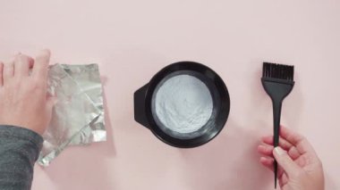 Siyah plastik bir kasede pembe arka planda saç boyası tozu..