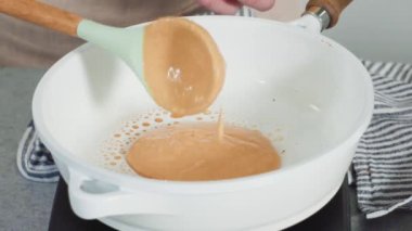 Time lapse. Step by step. Frying pumpkin pancakes batter on a white frying pan.