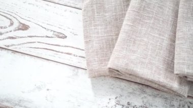 Yeni keten yemek peçetesini beyaz ahşap bir masada katlıyorum..