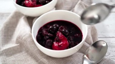 Ev yapımı böğürtlen kompostosu ahşap bir masada küçük beyaz kaselerde..