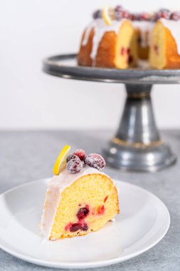 Dilimlenmiş limonlu kek. Şeker kızılcıkları ve limon dilimleri ile süslenmiş..