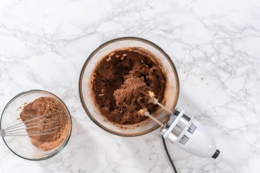 Flat lay. Mixing ingredients with a hand mixer to bake chocolate cookies with chocolate hearts for Valentines Day.