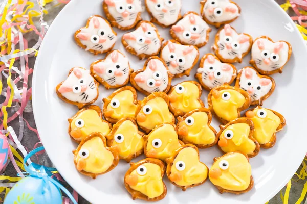 Easter chocolate-covered pretzel bunnies and ducklings on a white serving plate for the Easter table.