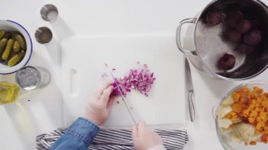 Düz yatıyordu. Adım adım. Sirkeli salata için beyaz bir kesme tahtasındaki sebzeleri dilimliyorum..