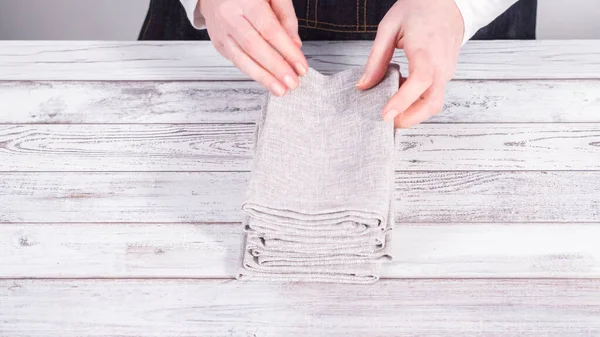 stock image Step by step. Folding natural color linen dinner napkin on a wooden white table.