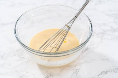 Amerikan bayrağı mini kekleri yapmak için ıslak malzemeleri büyük bir bardakta karıştırıyorum..