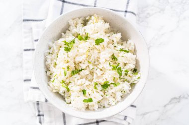 Cilantro Lime Rice. Beyaz seramik kaselerde taze maydanozla süslenmiş kişniş limonlu pirinç servis ediliyor..