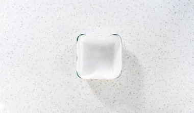 Düz yatıyordu. Kabak aromalı şekerleme hazırlamak için parşömen kağıdıyla kaplanmış kare cam fırın tavasına şekerleme dökülüyor..