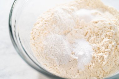 Beyaz çikolatalı macadamia fındığı pişirmek için bardakta çırpma kabıyla kurutulmuş malzemeleri karıştırıyorum..