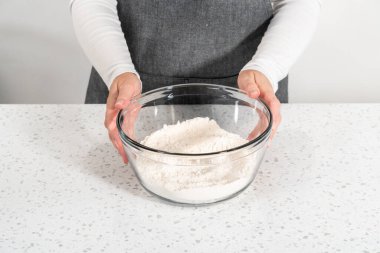 Basit bir vanilyalı kek pişirmek için büyük bir bardakta çırpma kabıyla kuru malzemeyi karıştırıyorum..