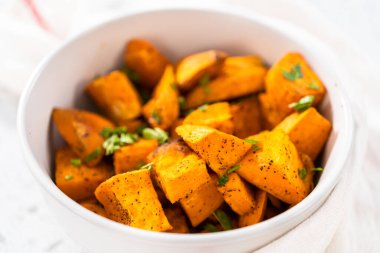 Beyaz seramik bir kasede fırında tatlı patates servis ediyorum..