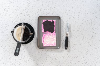 Flat lay. Filling Halloween silicone mold with melted chocolate to make chocolate decor for pretzels.