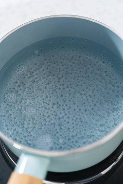 Çikolata parçacıkları ve diğer malzemeleri kaynayan suyun üzerine karıştırıp kabak aromalı şekerleme hazırlıyorum..