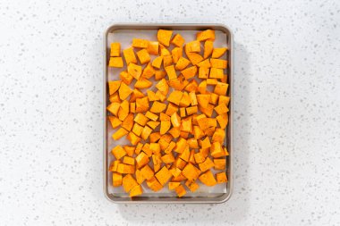 Düz yatıyordu. Fırında kızartılmış tatlı patates yapmak için parşömen kağıdıyla kaplı fırında tatlı patatesler..