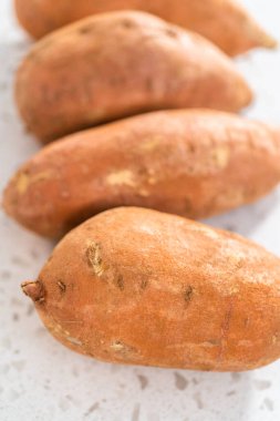 Fırında kızartılmış tatlı patates yapmak için cam karıştırma kabında ölçülmüş malzemeler.