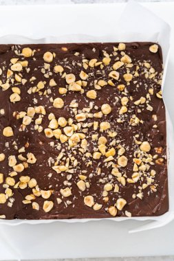Çikolatalı fındıklı şekerlemeyi parşömenle kaplı kare bir cheesecake tavasından kaldırıyorum..