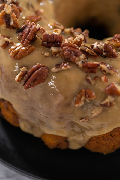 Freshly baked chocolate pumpkin bundt cake with toffee glaze topped with toasted pecans.