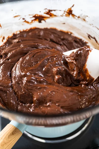 チョコレートのヘーゼルナッツ ファッジを調製するために沸騰した水の上にガラス混合ボウルにチョコレートチップやその他の成分を溶かす — ストック写真