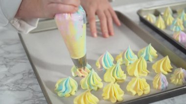 Adım adım. Tek boynuzlu at meringue kurabiyelerini parşömen kağıdıyla kaplanmış fırın kağıdına yapıştırıyorum..