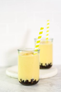 Taze yapılmış mango boba smoothie. Kağıt kamışla içme bardağında..