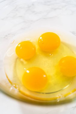 Büyük bir bardakta ıslak malzemeler karıştırarak kırmızı kadife kekler ve beyaz çikolatalı ganache kreması pişiriyorum..