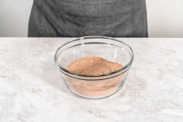 stock image Mixing ingredients in a glass mixing bowl with a blending whisk to bake chocolate strawberry cupcakes.