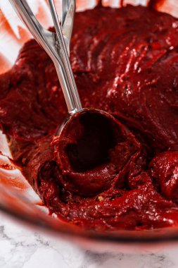 Kek hamurunu hamur kepçesiyle kek tepsisine doldurmak folyo kaplamalarla kaplanmış beyaz çikolatalı ganache kremalı kırmızı kadife kekler pişirmek.