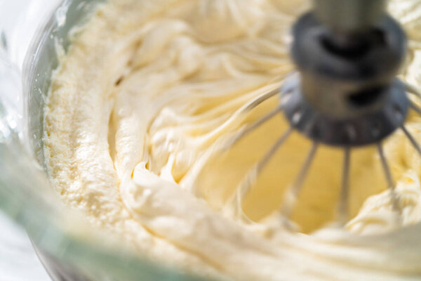 Whipping white ganache in kitchen mixer to make the white chocolate ganache frosting.