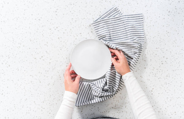 Flat lay. Empty a white plate with a kitchen towel on the white kitchen counter.