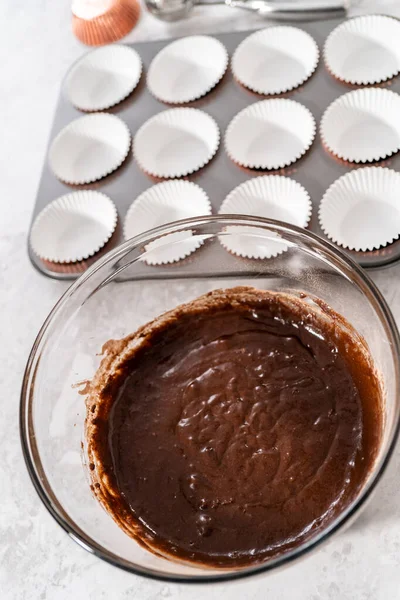 カップケーキの生地をカップケーキライナーにすくってチョコレートストロベリーカップケーキを焼く — ストック写真