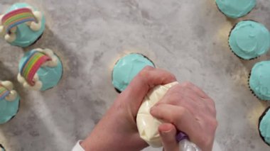 Düz yatıyordu. Çikolatalı kekleri tereyağlı krema ve gökkuşağı şekeriyle süslüyorum..