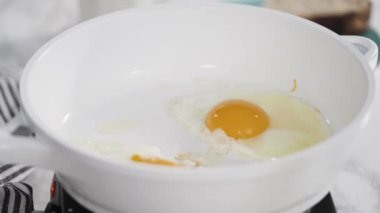 Manzarayı kapat. Beyaz tavada taze yumurta kızartıyorlar..