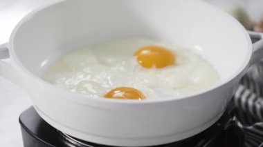Time lapse. Close up view. Frying farm fresh eggs in a white skillet.