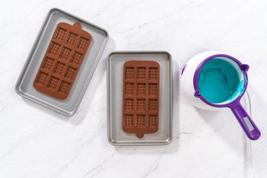 Düz yatıyordu. Çikolata kalıplarını erimiş çikolatayla doldurarak küçük denizkızı çikolatalarını hazırlıyorum..