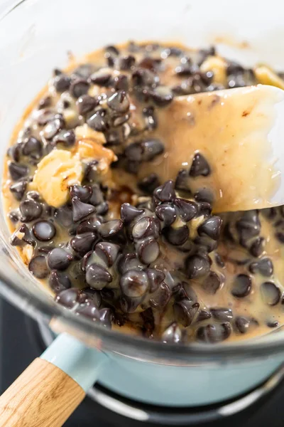 stock image Melting chocolate chips and other ingredients in a glass mixing bowl over boiling water to prepare chocolate fudge with peanut butter swirl.