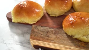 Adım adım. Odun kesme tahtasının üzerinde taze pişmiş çörekleri dilimliyorum..