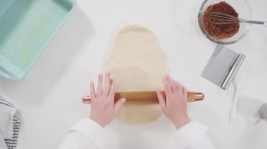 Düz yatıyordu. Tarçınlı rulo yapmak için Fransız merdanesiyle yuvarlanan hamurlar..