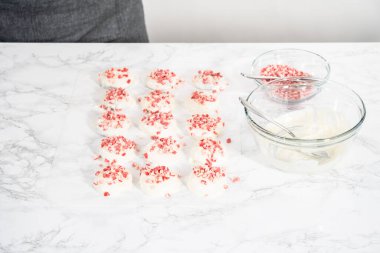 Naneli beyaz çikolatalı kurabiyeler hazırlamak için eritilmiş beyaz çikolataya çikolatalı kurabiyeler batırmak..