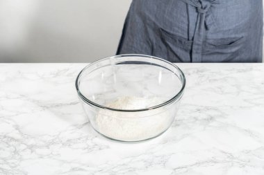 Lemon wedge cookies with lemon glaze. Mixing dry ingredients with a hand whisk in a large glass mixing bowl to bake lemon wedge cookies.