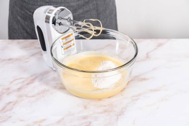 Elmalı Sharlotka keki pişirmek için karışımı büyük bir bardakta karıştırıyorum..